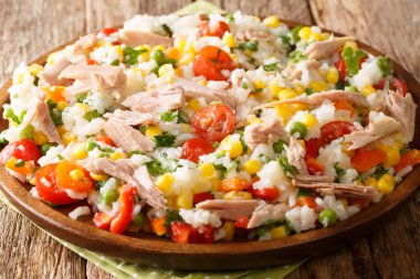 Ton balıklı pilav, domates, tatlı biber, mısır, yeşil bezelye ve otlar. Masada yakın plan. Yatay