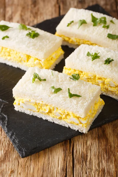 白いパンのスライスの間に隠された卵のサラダ 日本の卵のサンドイッチ卵のサンドは テーブルの上にボード上に閉じます ベルティカ — ストック写真