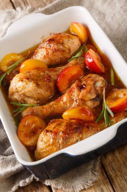 Erikli soslu fırında tavuk budu ve biberiyenin yakın çekimi masada. dikey