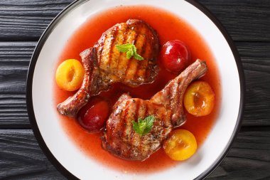 Lezzetli ızgara domuz pirzolası, taze erik ve meyve sosu tabakta yakın plan. Yukarıdan yatay üst görünüm