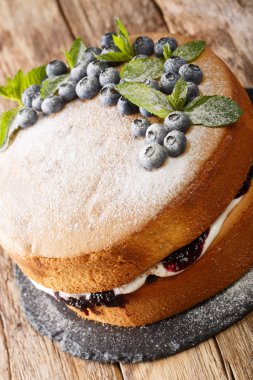 Yumuşak vanilyalı pasta, bir kat yabanmersini reçeli ve bir tutam krem şanti Victoria 'yı masadaki tahtada İngiliz klasik yakın çekimi yapar. Dikey