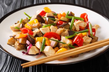 Çin usulü kızarmış tavuk, patlıcan, biber ve soğan ve baharatlı soya sosuyla masada yakın plan. yatay