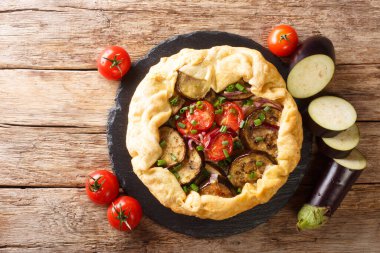 Masanın üzerinde domatesli, soğanlı ve otlu patlıcan turtası. Yukarıdan yatay üst görünüm