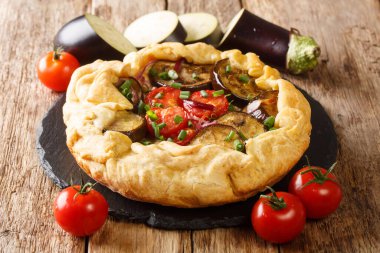 Masanın üzerinde domatesli, soğanlı ve otlu patlıcan turtası. Yatay