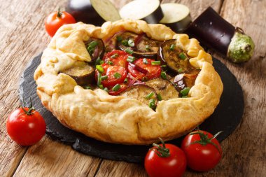 Masadaki tahtaya yakın plan domatesli, soğanlı ve otlu taze fırınlanmış patlıcan turtası. yatay