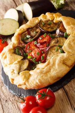 Masanın üzerinde domatesli, soğanlı ve otlu vejetaryen patlıcan turtası var. dikey