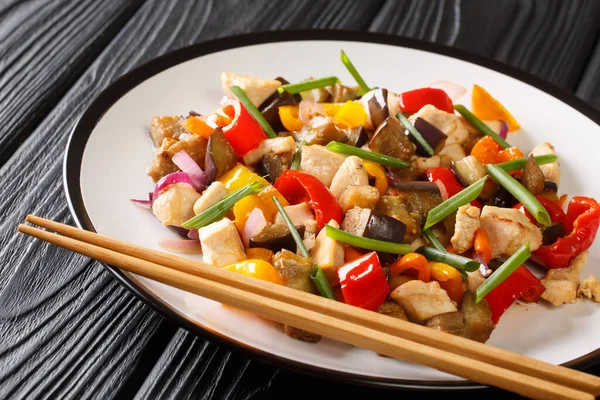 Asya yemekleri kızarmış tavuğu patlıcan, biber ve soğanla karıştırıp masaya yakın plan baharatlı soya sosu koyar. yatay