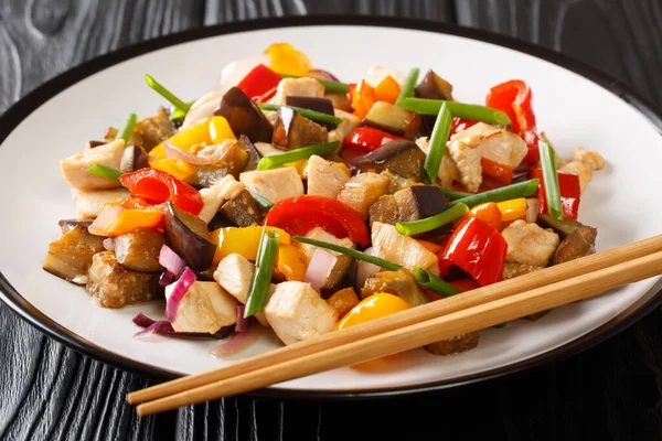 Çin usulü kızarmış tavuk, patlıcan, biber ve soğan ve baharatlı soya sosuyla masada yakın plan. yatay