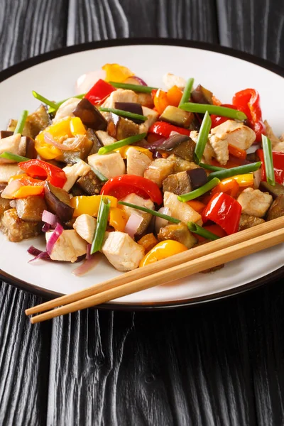 Masadaki tabakta patlıcanlı, biberli ve soğanlı tavuk kızartması. dikey