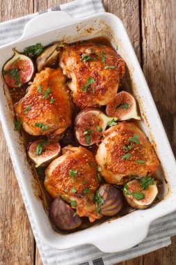 Baharatlı tavuk butları taze incir ve bitkilerle pişirilmiş. Masanın üzerinde yakın plan bir yemek tabağında. Yukarıdan dikey üst görünüm