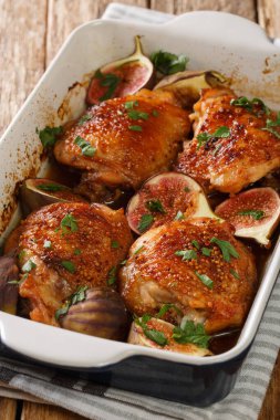Baharatlı tavuk butları taze incir ve bitkilerle pişirilmiş. Masanın üzerinde yakın plan bir yemek tabağında. dikey