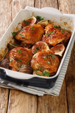Akdeniz menüsü tavuk butları olgun incir ve bitkilerle pişirilmiş. Masanın üzerinde bir fırın tabağında yakın plan. dikey