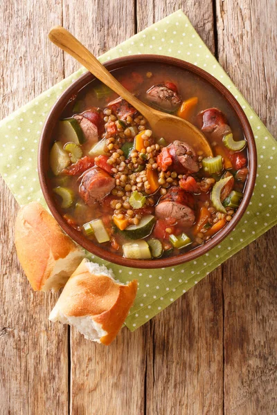 Sausage lentil soup with tomatoes, zucchini, carrots, celery and onions close-up in a plate on the table. vertical top view from abov — Stock Image Sausage Lentil Soup Tomatoes Zucchini Carrots Celery Onions Close Plate Stock Image