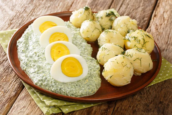 German style dish of potatoes, boiled eggs and green sauce close-up in a plate on the table. horizonta