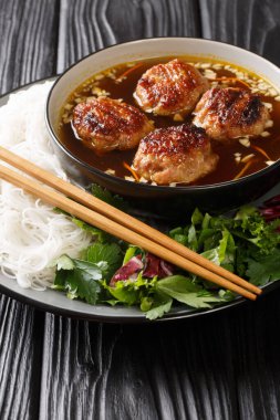 Bun cha, pirinç vermicelli noodle (çörek), ızgara domuz eti (cha) ve masadaki tabakta yakın plan et suyundan oluşur. Dikey