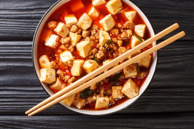 Aromatik ve baharatlı bir sosta pişirilmiş yumuşak mapo tofu ve masada kıymalı et yakın plan eşliğinde. Yukarıdan yatay üst görünüm