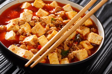 Aromatik ve baharatlı bir sosta pişirilmiş yumuşak mapo tofu ve masada kıymalı et yakın plan eşliğinde. Yatay