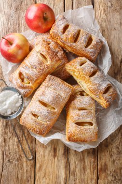 Ahşap bir masanın üzerinde elmalı taze pişmiş puf böreği. Yukarıdan dikey üst görünüm