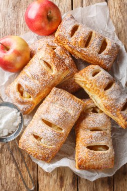 Tahta bir masanın üzerinde pudra şekerle kaplanmış Danimarka elmalı puf böreği. Yukarıdan dikey üst görünüm