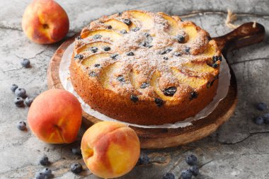tatlı ve basit şeftali ve yabanmersinli kek. Masanın üzerindeki tahtanın üzerinde basit bir vanilyalı sünger kapağı var. Yatay