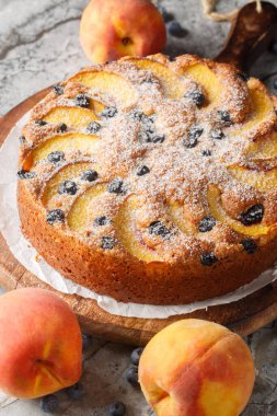 Masadaki tahtada taze yaz meyvesi yakın planlı yaban mersini şeftalili kremalı pasta. Dikey