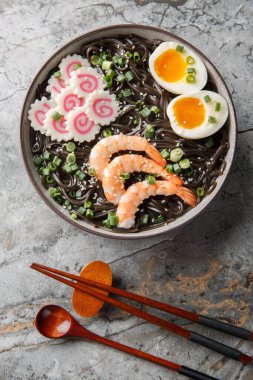 Japon soba çorbası, karides, kamaboko, yeşil soğan ve yumurtanın yakın çekimi masanın üstünde. Yukarıdan dikey üst görünüm