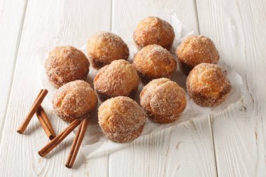 Mini Tarçın Şekeri çörekleri kek tavasında pişirilmiş yoğun kek tarzı çörekler ve ahşap masada yakın plan tarçın ve şekerle kaplanmış. Yatay