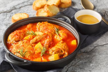 Chicken Bouillabaisse is comforting stew featuring tender chicken pieces simmered in a saffron-tomato broth infused with garlic, fennel, and white wine closeup in the saucepan on the table. Horizonta