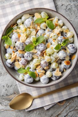 Close-up of grape mix salad with almonds dressed with creamy cheese sauce in a plate on the table. Vertical top view from abov
