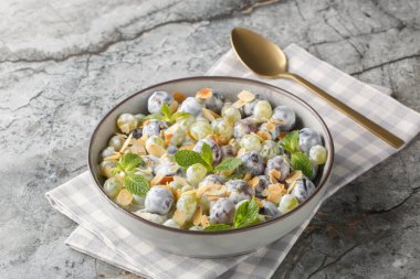 Fresh sweet Sultana grape salad with almond flakes, mint, Greek yogurt and cream cheese dressing close-up in a plate on the table. Horizonta