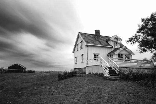 White wooden Scandinavian house, Rorbu, clouds in slow motion. Black&white photography.