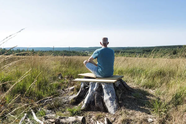 Mann mit Dose sitzt auf Baum und macht Yoga — Stockfoto