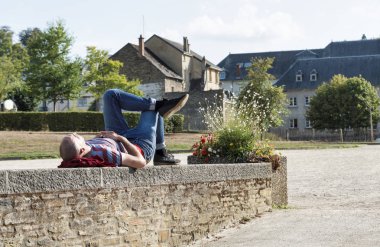 bir duvarda oturan adam