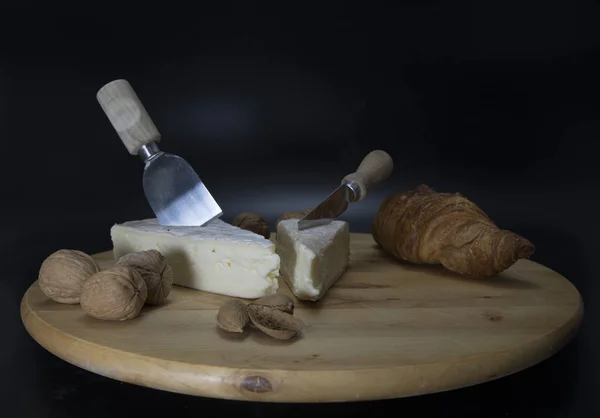 ナイフとフランスのクロワッサンとクルミとアーモンドとブリーと呼ばれるフランスのチーズと木製の回転可能なプレート — ストック写真