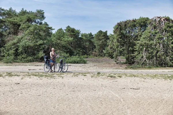 Mujer en una bicicleta en el parque nacional el hooge veluwe — Foto de Stock