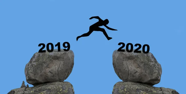 Człowiek skok między 2019 i 2020 lat od jednej skały do innej skały — Zdjęcie stockowe