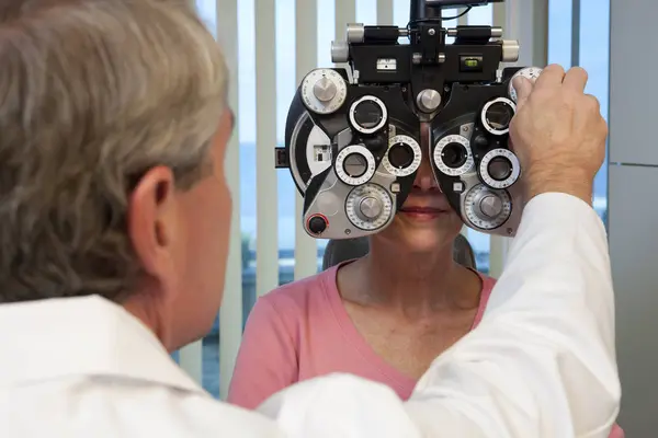 眼科医生用屈光镜检查妇女的眼睛 — 图库照片