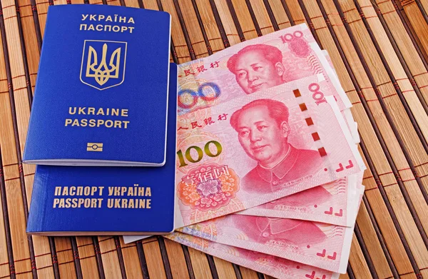 Ukraynalı pasaport ve Yuan closeup arka plan bambu hasır üzerinde