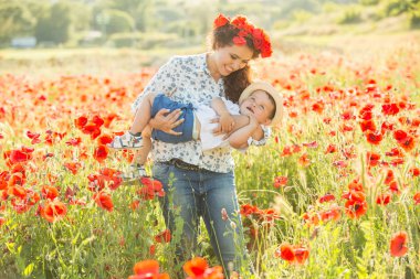 Ailesiyle haşhaş tarlasında gülümseyen esmer. Anne ve oğlu yürüyüşe çıktılar. Yaşam tarzı fotoğrafı.