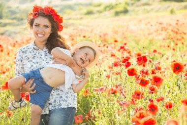 Ailesiyle haşhaş tarlasında gülümseyen esmer. Anne ve oğlu yürüyüşe çıktılar. Yaşam tarzı fotoğrafı.