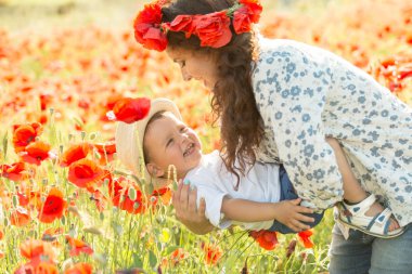 Ailesiyle haşhaş tarlasında gülümseyen esmer. Anne ve oğlu yürüyüşe çıktılar. Yaşam tarzı fotoğrafı.