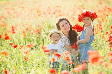 Ailesiyle haşhaş tarlasında gülümseyen esmer. Annem ve çocukları yürüyüşe çıktı. Yaşam tarzı fotoğrafı.