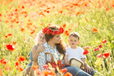 Ailesiyle haşhaş tarlasında gülümseyen esmer. Annem ve çocukları yürüyüşe çıktı. Yaşam tarzı fotoğrafı.
