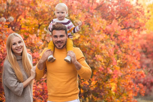 結婚した夫婦と彼らの小さな娘は秋の森を歩いている 人々は白いパンツと鮮やかな色のセーターを着ています 健康的なライフスタイル 家族の価値 — ストック写真