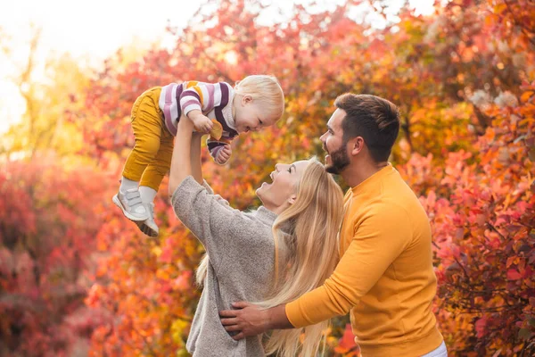 結婚した夫婦と彼らの小さな娘は秋の森を歩いている 人々は白いパンツと鮮やかな色のセーターを着ています 健康的なライフスタイル 家族の価値 — ストック写真