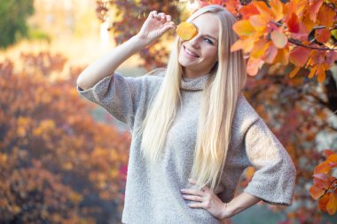 Sonbahar ormanında kısa kollu, örgülü, moda süveter giyen uzun saçlı sarışın. Sağlıklı saçlar ve cilt. Sağlığınıza dikkat edin.