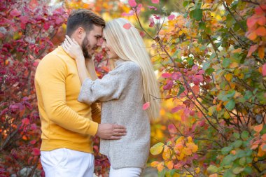 Sarı kazaklı, sakallı genç bir adam uzun saçlı bir sarışına sarılıyor. Tatilde olan evli bir çift. Balayı