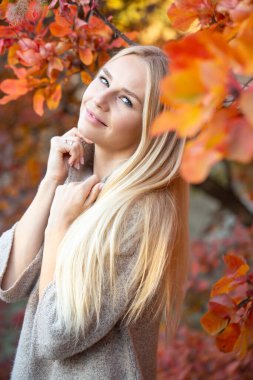 Sonbahar ormanında kısa kollu, örgülü, moda süveter giyen uzun saçlı sarışın. Sağlıklı saçlar ve cilt. Sağlığınıza dikkat edin.