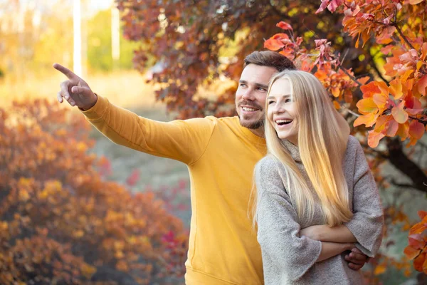 一个留着整洁胡子 穿着黄色毛衣的年轻人拥抱着一个长长的金发姑娘 一对夫妇在度假 Honeymoon — 图库照片