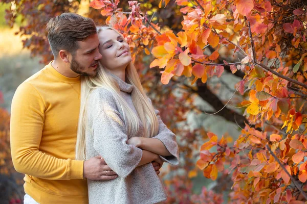一个留着整洁胡子 穿着黄色毛衣的年轻人拥抱着一个长长的金发姑娘 一对夫妇在度假 Honeymoon — 图库照片